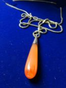 An orange mineral drop pendant on a fine nine carat gold box chain.
