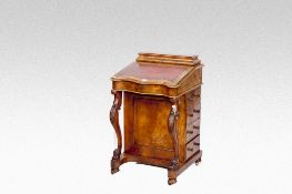 A Victorian walnut serpentine front Davenport desk with `piano` carved legs.