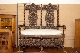 A heavily carved hardwood two seater sofa, the twin panelled backs having spiral twist uprights
