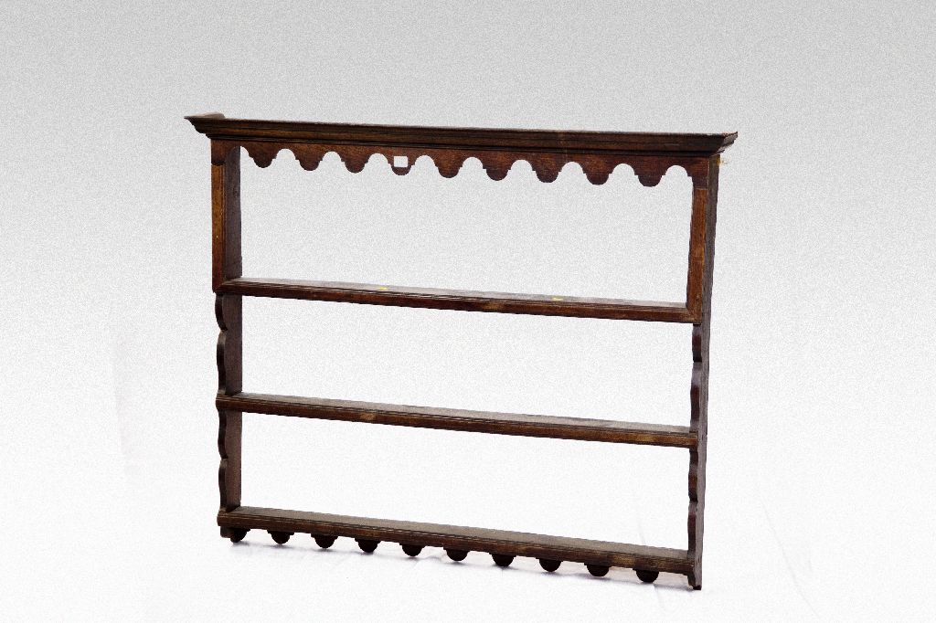 A three shelf open backed oak Delft rack with shaped apron and shaped side uprights, 52 ins (132