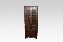 A reproduction dark wood one piece corner cupboard with leaded upper panels.