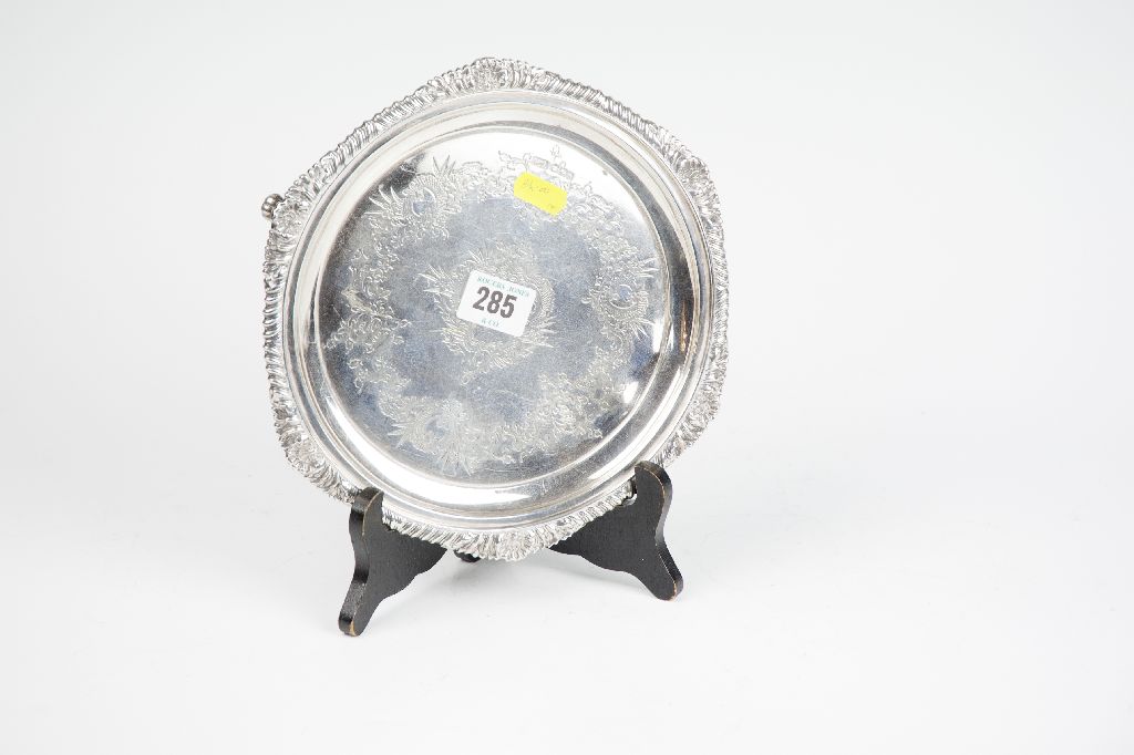 A small circular bright cut salver with feather edge and shell border on three supports (slight