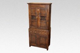 A compact polished oak and pine two piece bread and cheese cupboard having a two door upper