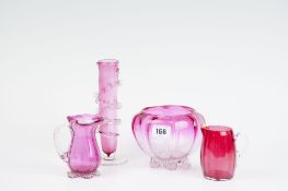 Four pieces of cranberry glass ware being a bowl on plain footed base, two cream jugs, and a posy