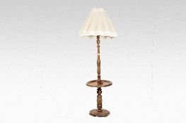 A polished and carved standard lamp having a circular shelf to the column on a circular carved base,