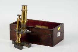 A mahogany encased brass microscope on a slate base, maker unattributed, lid absent from case.