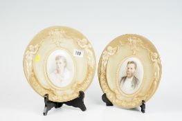 A pair of circular Doulton Burslem blush decorated wall plaques, each depicting a painted