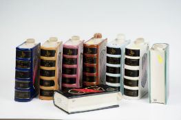 A set of eight Govancroft Pottery spirit flasks in the form of books, in harlequin coloured volume
