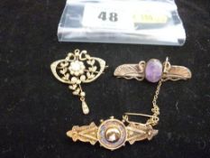 A seed pearl gold drop pendant; and two nine carat gold bar brooches, one with decorative purple