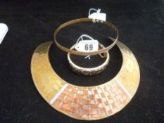 A brass and copper Indian collarette, a yellow metal Grecian key patterned bangle and a nine carat
