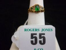 An eighteen carat gold emerald dress ring, the centre oblong cut emerald having flanking tiny