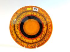 POOLE A `Saturn` shallow dish in mottled tangerine and black disc design, 10 ins (26 cms) diameter