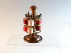 An Edwardian rosewood bobbin reel with column with pincushion to top and stepped circular base