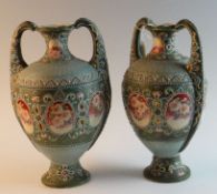 A pair of Continental pottery twin handled vases with profuse floral enamel style decoration, 13.5
