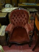 A Victorian walnut framed armchair with carved floral decoration on cabriole ball feet and with