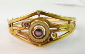 A GOLD AND PURPLE STONE BANGLE; Victorian style with open target style mount set with round mixed