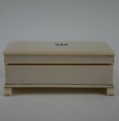 An early 20th Century ivory trinket box of rectangular form on four legs and with detachable lid,