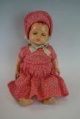 An early to mid 20th Century doll, ceramic head and body with original pink polka dot dress and