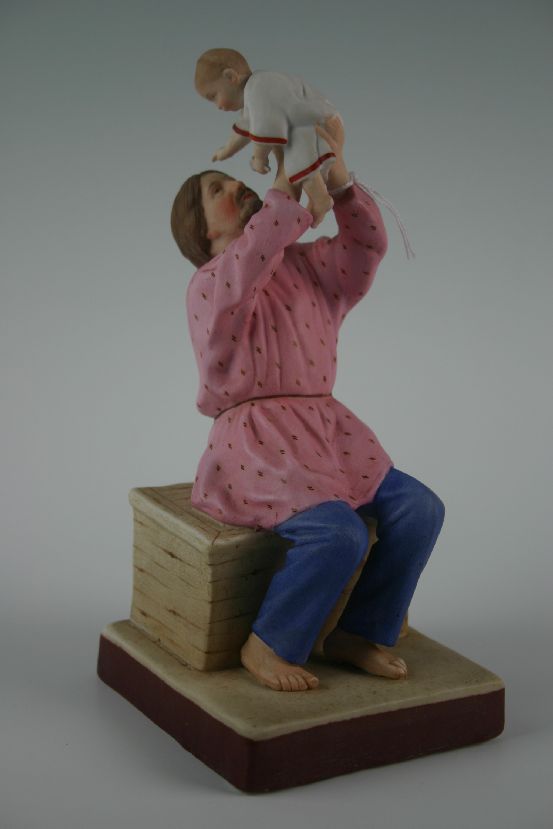 A 19th Century Russian parian figure of peasant father and infant aloft of Biblical colouring, 8.5