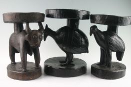 Group of eight ebonized carved native stools with primitive animals and fish columns