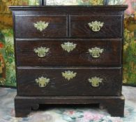 A polished dark wood reproduction chest of two long and two short drawers with brass drop handles on