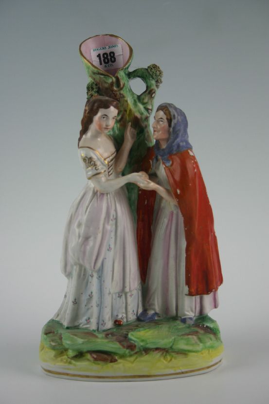 A Staffordshire spillholder group of a young lady having her palm read by an old lady in red