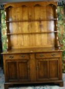 A reproduction polished cottage dresser having a shaped hood and two shelves to the top over a