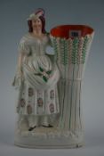 A Staffordshire figural spillholder with lady in floral dress and feathered cap and stook of corn,