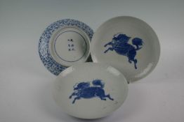 A trio of Chinese plates each decorated with blue mythical hoofed beasts on floral relief and having