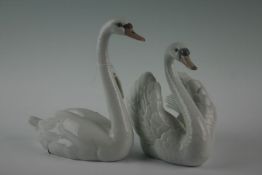 Two Lladro ceramic swans, serial numbers 5230 and 5231, 8.5 ins (22 cms) and 7.5 ins (19 cms) high