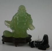 An Oriental jade coloured `laughing Buddha` on wooden plinth, and a stone black coloured seal