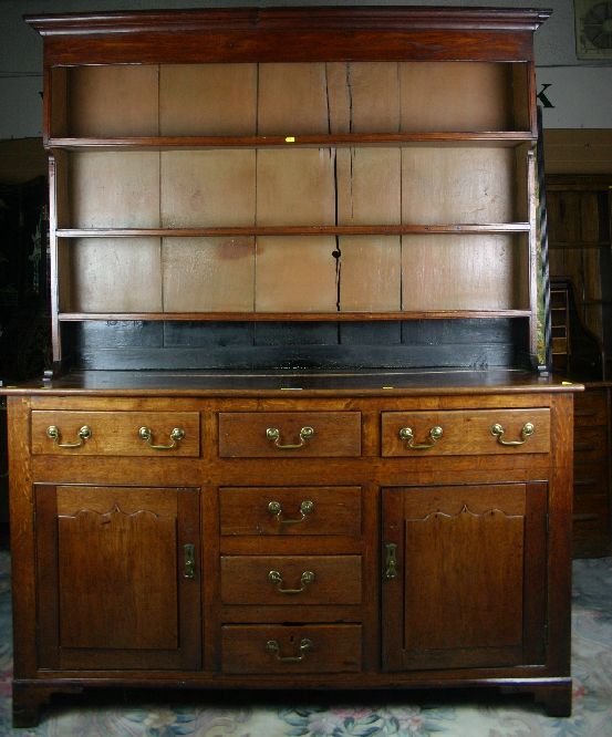 An early 19th Century oak Welsh dresser having a three shelf rack over a base having four opening