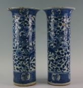 A pair of Chinese blue and white tall chimney vases with flared necks profusely decorated with a