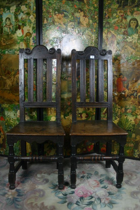 A pair of 18th Century carved oak hall chairs having shaped and carved top rails with three reeded