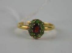 Ladies` gold (15ct) peridot and garnet dress ring with oval mixed cut garnet in raised eight claw