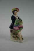 A 19th Century Staffordshire seated gentleman with grocery basket, 8.5 ins (21.5 cm)