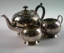 A three piece silver plate tea service. Of compressed circular form with engraved scrolled