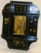 A late 19th Century ebonised and hand decorated wall hanging with central rectangular bevelled