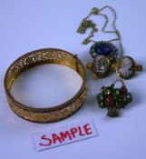 A yellow metal (possibly Indian) and blue enamel bangle with pierced foliate scrolled decoration