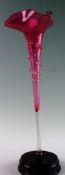 A Victorian cranberry lustre flute with attached leaf style decoration and waved rim on base