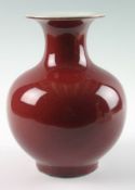 A nineteenth century Chinese flambé pear shaped vase, covered in a red glaze, the flared rim covered