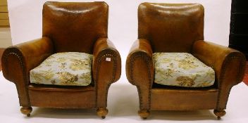 A pair of circa 1920s leather club chairs with stud decoration and later floral textile cushions