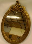 An early twentieth century Florentine carved giltwood wall mirror of oval form with foliate scroll