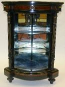 A late 19th Century ebonised, amboyna and gilt corner cabinet with two glass shelves flanked by