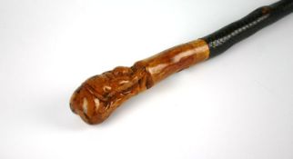 An interesting early to mid twentieth century walking stick with walnut carved handle in the form of