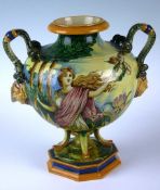A majolica style twin handled classical urn with satyr masks underneath serpent handles, with a
