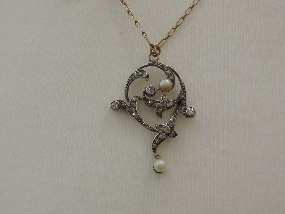 A white metal pendant of open foliate form set with diamonds and cultured pearl with further pearl