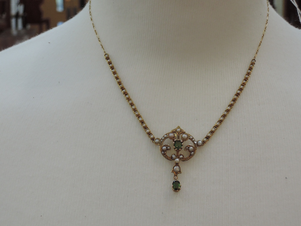 An Edwardian necklace having central peridot with seed pearl foliate decoration with peridot dropper