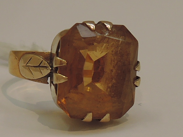 A ladies dress ring having large yellow non precious stone in raised mount with claw setting and
