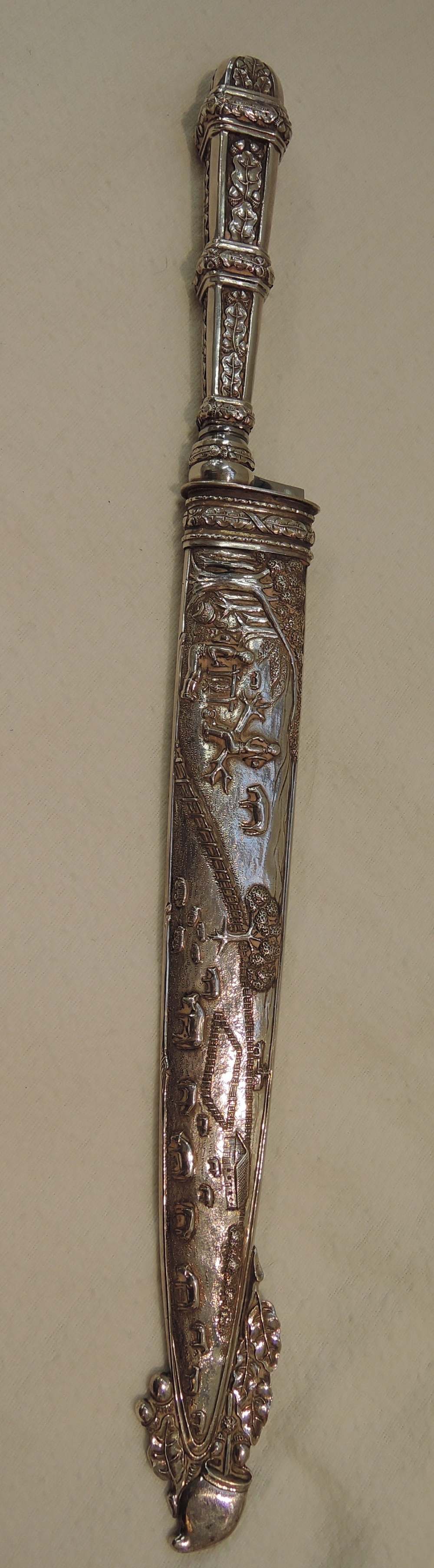 A cased white metal knife, possibly continental silver, having embossed rural industry decoration